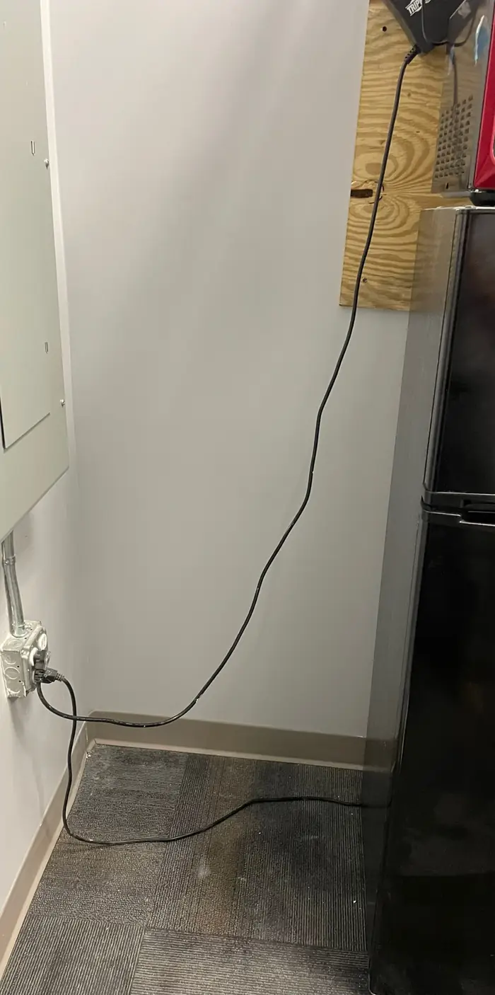 A drywall wall patched and finished flat beside a refrigerator, the floor swept clean